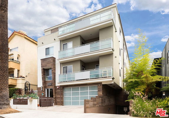 Front view of a modern multi-story building with balconies and a garage.