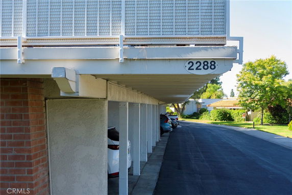 Covered parking area with multiple vehicles and a row of parking spaces.