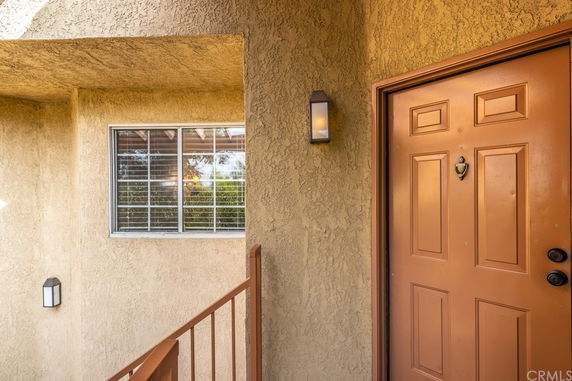 Exterior view of an entrance door with a textured wall and window.
