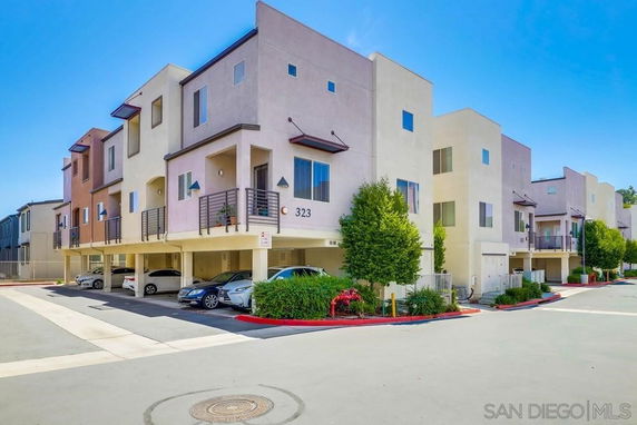 Front view of a multi-story residential building with balconies and parking underneath.