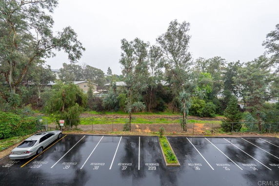 Outdoor parking area with reserved parking spaces in front of a wooded area.