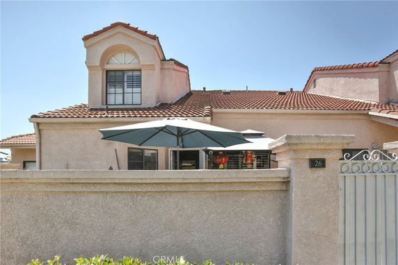 Front view of a house with a tiled roof and a patio with an umbrella.