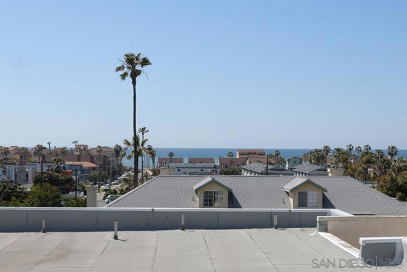 Panoramic view from a rooftop overlooking coastal buildings and the sea in the distance.