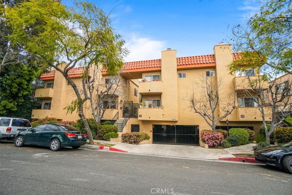 Front view of a multi-story apartment building with a tiled roof and balconies.