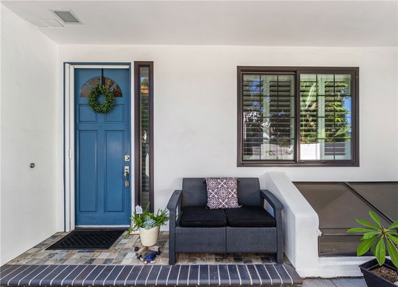 Front view of a house entrance with a blue door and a small seating area.