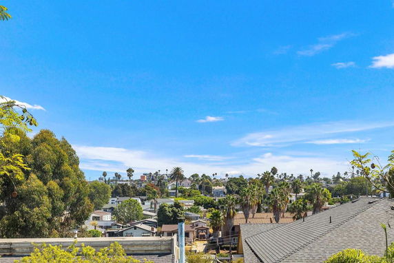 Panoramic view of a suburban area with houses and trees under a clear blue sky.