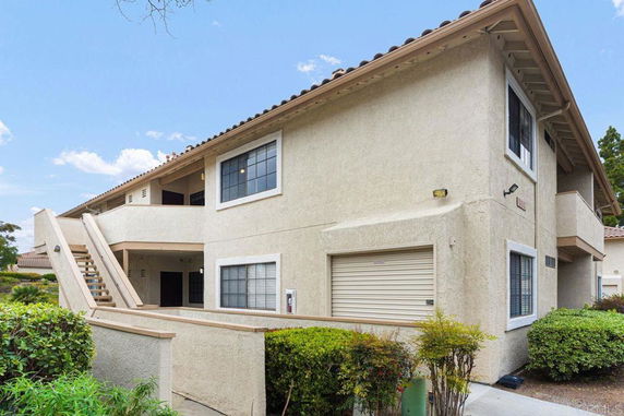 Front view of a two-story residential building with exterior stairs and a garage.