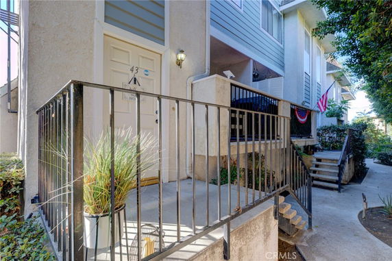 Front view of a multi-level residential building entrance with a small porch and railing.
