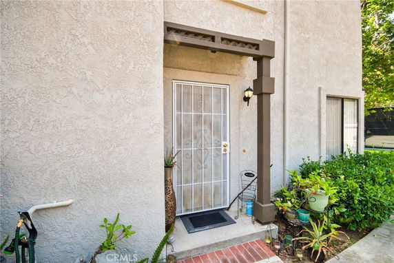Front view of a house entrance with metal screen door, plants, and outdoor lighting.