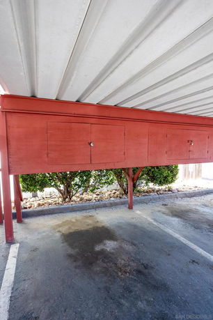 Covered parking area with a metal roof and red storage compartments.