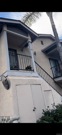 Front view of a two-story residential building with a staircase leading to an upper-level entrance.