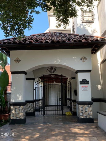 Front view of a building entrance with a tiled roof and gated archway.