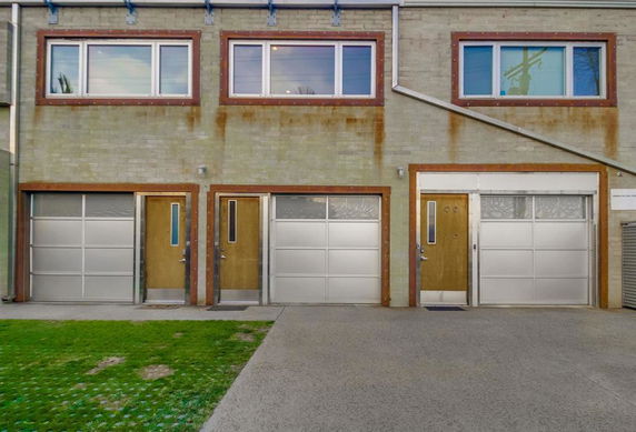 Front view of a building with three metal garage doors and windows above.