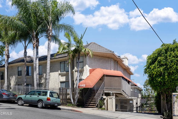 Front view of a multi-story building with a stairway and covered entrance.