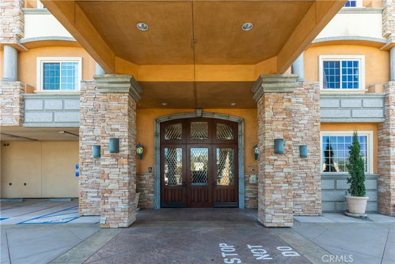 Front view of a multi-story building entrance with stone and stucco facade.