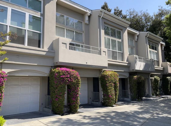 Front view of a row of modern townhouses with garages and balconies.