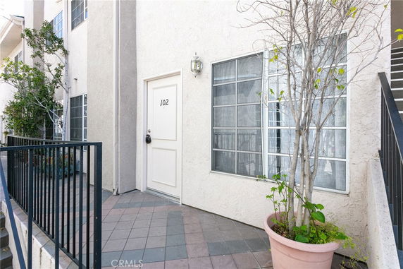 Front view of a residential building entrance with a door marked 102 and a large window.