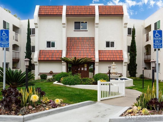 Front view of a multi-story building with red-tiled roof elements and accessible parking.