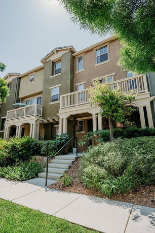 Front view of a multi-story residential building with balconies and steps leading to the entrance.