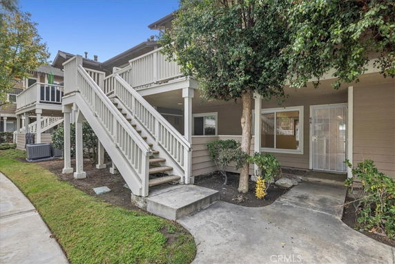 Front view of a two-story residential building with exterior stairs and a small porch area.