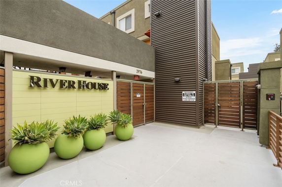 Front view of a building with a decorative wall featuring the name 'River House' and green potted plants.