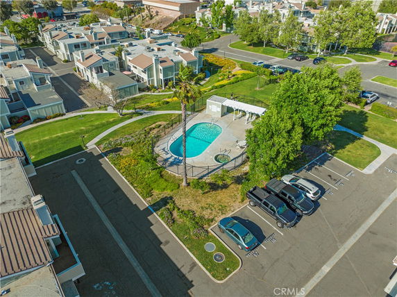 Aerial view of a swimming pool surrounded by residential buildings and a parking area.