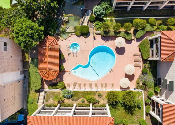 Aerial view of an outdoor swimming pool with a surrounding patio and poolside furniture.