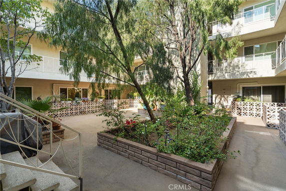 View of a courtyard of a multi-story building with trees and decorative railings.