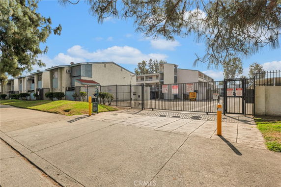 Front view of a multi-story apartment complex with gated entrance.