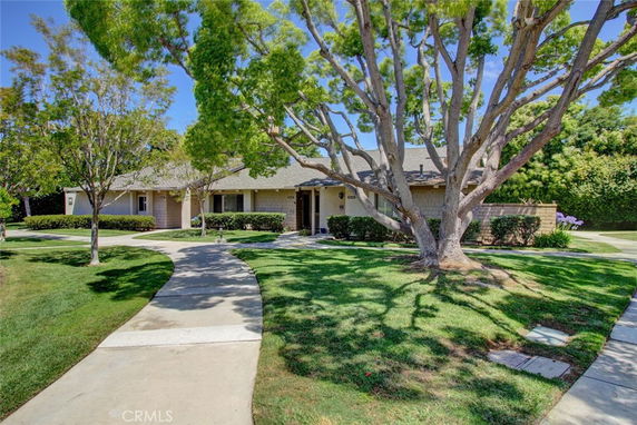 Front view of a single-story house with a shaded walkway and mature trees.