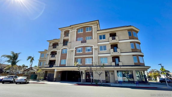 Front view of a multi-story building with balconies and ground-level commercial space.