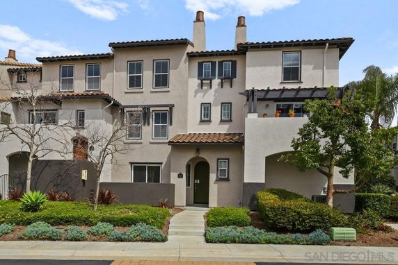 Front view of a multi-story house with arched entryway and balcony.