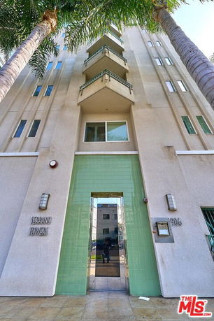 Front view of a multi-story building with balconies and green entrance tiles.