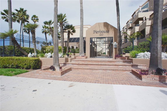 Front view of Pierhouse building with gated entrance and palm trees.