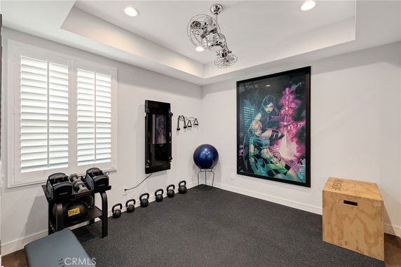 Interior of a home gym with exercise equipment and a large poster on the wall.