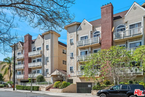 Front view of a multi-story residential building with balconies and brick chimneys.
