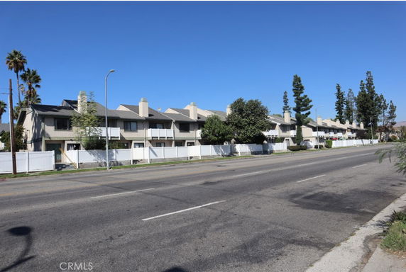 Front view of a row of townhouses with balconies and chimneys.