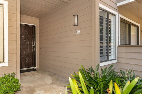Front entrance of a house with a covered porch and window with shutters.