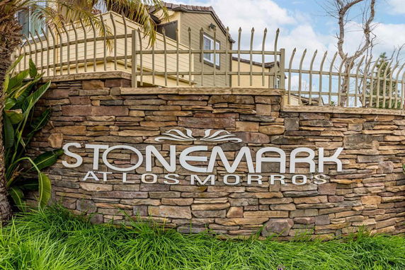 Front view of a building with a stone wall and gated fence.