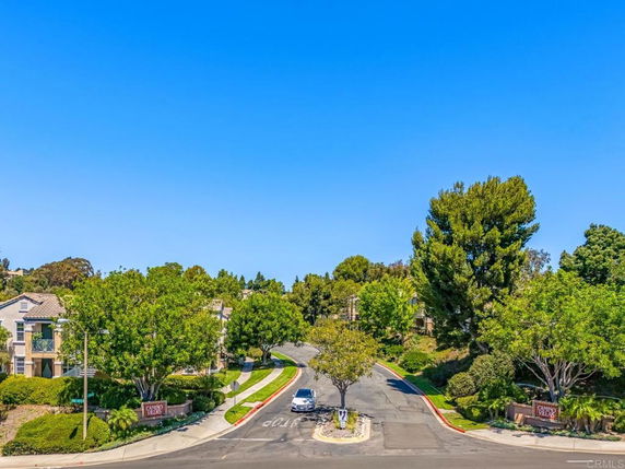 View of a suburban street with houses and trees lining the road.