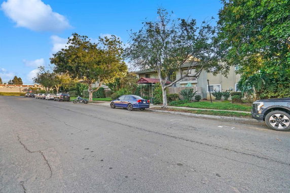 Street view with parked cars and trees in front of a building.
