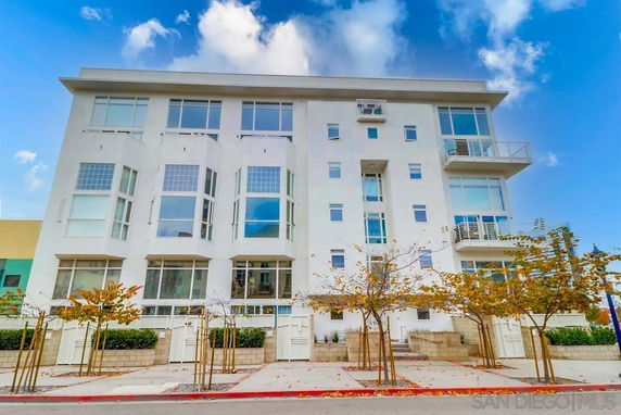 Front view of a multi-story modern apartment building with large windows.