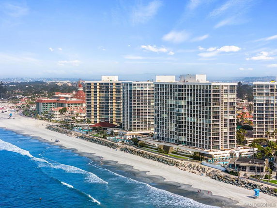 Aerial view of tall residential buildings along a beachfront with ocean waves.