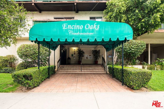 Front view of a condominium with a green canopy entrance.