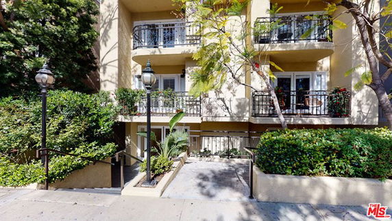 Front view of a multi-story building with balconies and greenery.