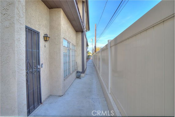 Side view of a house with a narrow walkway beside a tall fence.