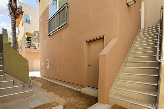 Outdoor view of a multi-story residential building with stairs and entry door.