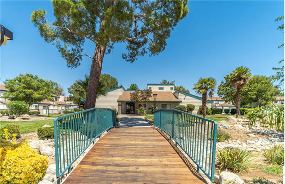 Front view of a building with a wooden bridge and landscaped surroundings.