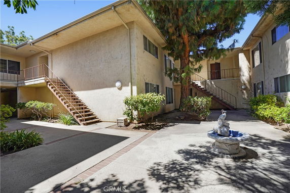 Courtyard view of a two-story apartment building with exterior staircase.