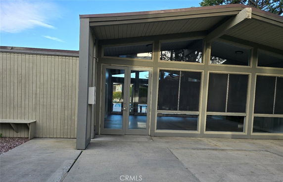 Front view of a building with large glass windows and a peaked roof.